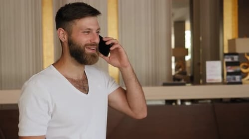 Closeup of a Bearded Man Talking on the Phone in the Hotel Lobby