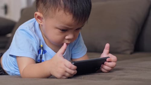Child Using Phone While Lying on Couch