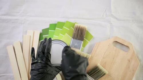 Paint in metal paint can and painters tools on a canvas drop cloth.