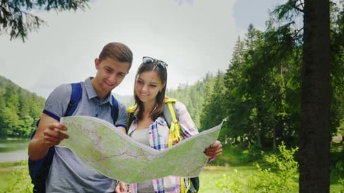 Young Couple Hiking and Reading a Map Outdoors