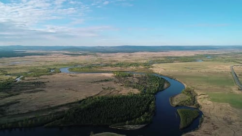 Aerial View of a River Flowing Through Rural Area with Meadows Rare Trees and with the Road on the