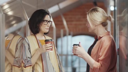Two Women Talking and Drinking Coffee at Work