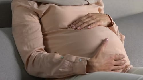 Pregnant Person Holding Stomach at Baby Shower Indoors
