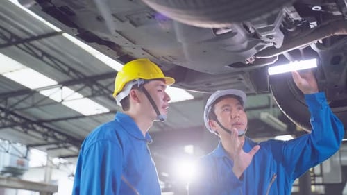 Asian two automotive mechanic men check and maintenance to repair engine machine in garage.