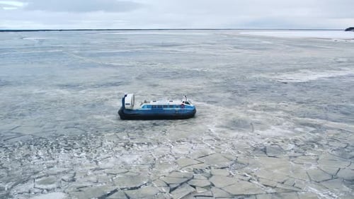 Hovercraft Gliding Across Frozen Ice Lake in Winter
