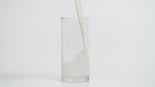 Movimiento superlento de verter leche en vidrio transparente