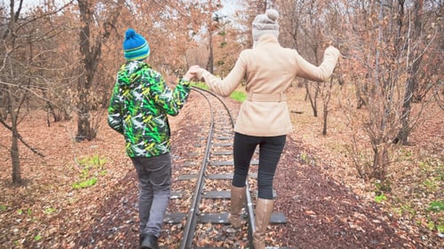 Couple Walking Hand-in-Hand on Train Tracks in Autumn