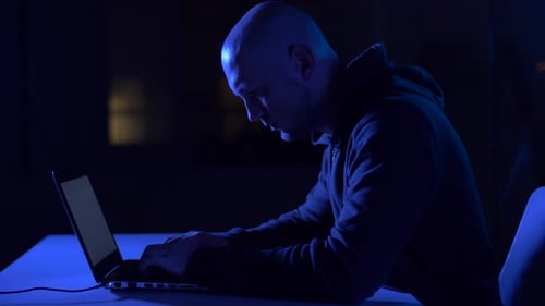Man typing on a laptop in dark room