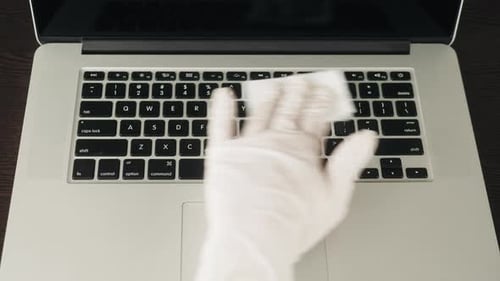 Gloved Hand Cleaning Laptop Keyboard with Wipe
