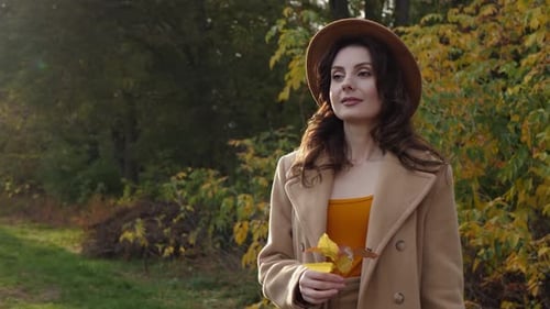 Stylish Woman Holds Autumn Leaves in Nature