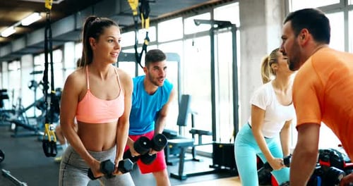 Adults Working Out with Dumbbells at Gym