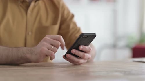 Gros plan des mains d'un jeune homme à l'aide de smartphone