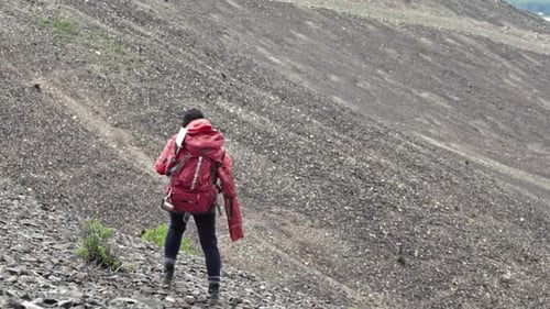 Vista trasera de mujer mochilera caminando en las montañas