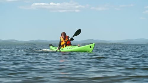 Man Paddling Kayak on Calm Lake Water