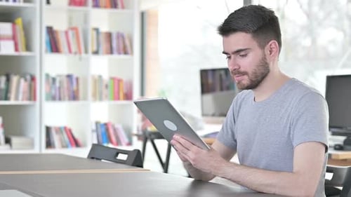 Serious Young Man Using Digital Tablet in Office