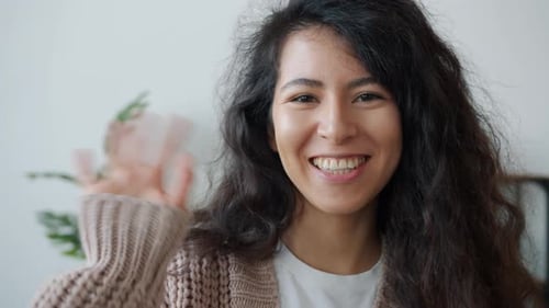 Smiling Woman Waving Hand in Greeting Indoors