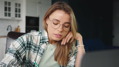 Nahaufnahme Porträt einer jungen, seriösen Studentin, die sich das Webinar online ansieht und sich zu Hause Notizen macht
