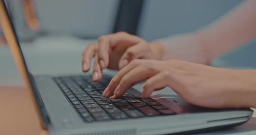 Hands Typing on Laptop Keyboard in Office