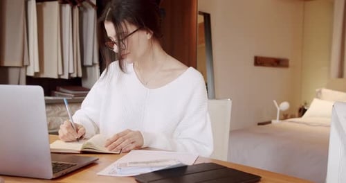 Woman Writing in Notebook at Desk Indoors