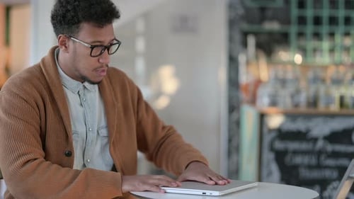 Afrikanischer Mann schließt Laptop beim Verlassen des Cafés