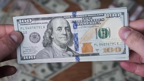 Dollars in Male Hands on Background of Table with Money
