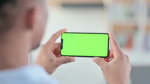 African Man Watching Smartphone with Green Chroma Key Screen