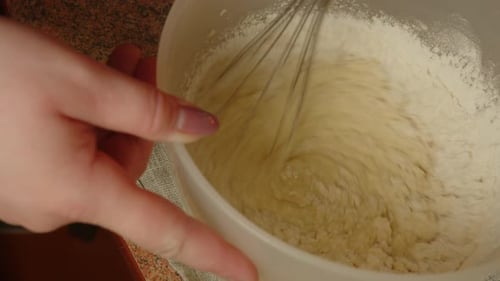 Unbekannte Person, die Teig in einer Schüssel mit Schneebesen umrührt