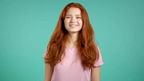 Young Teenager in Pink Looking To Camera and Smiling. Portrait of Beautiful Girl on Blue Wall Studio