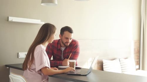 Woman and Man Working on Laptop in Kitchen