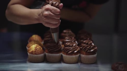 Woman squeezing cream on muffins