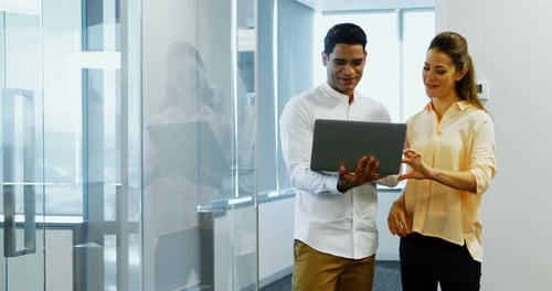 Man and Woman Collaborating on Laptop in Modern Office