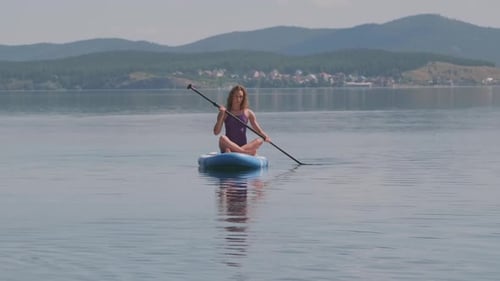 Woman Paddle Boarding on a Serene Lake