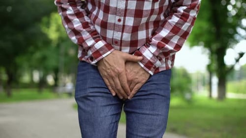 Adult experiencing lower abdomen discomfort outdoors