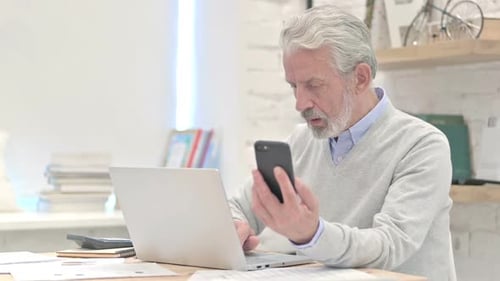 Senior Man Using Cell Phone at Desk