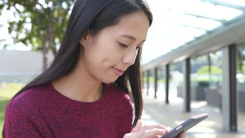 Woman Typing on Smartphone in Urban Setting