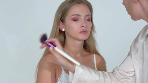 Makeup Artist Applying Blush to Young Woman