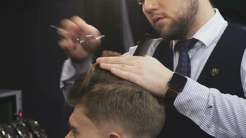 Abgeschnittene Aufnahme eines professionellen Friseurs, der seinem männlichen Kunden Haare schneidet