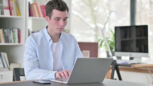 Young Man Working on Laptop at Desk