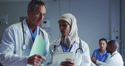Front view of Multi-ethnic doctors discussing over digital tablet in hospital