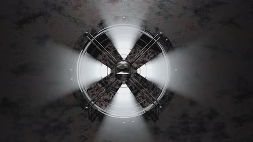 A huge old, rusty fan in the ventilation system rotates slowly and rays of light pass through it