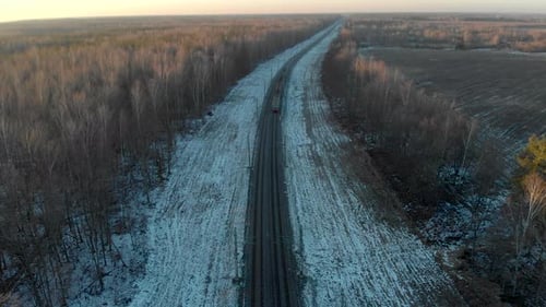 Passenger Train in the Winter Forest in the Evening. The Picturesque Landscape with the Railroad