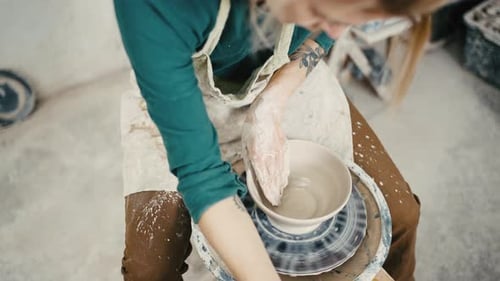 Above View of Female Potter Sculpting Ceramic Pottery on Spinning Pottery Wheel Using Water Tracking