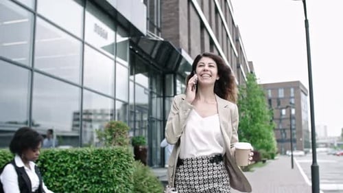 Woman Walking, Talking on Phone, Coffee in Hand