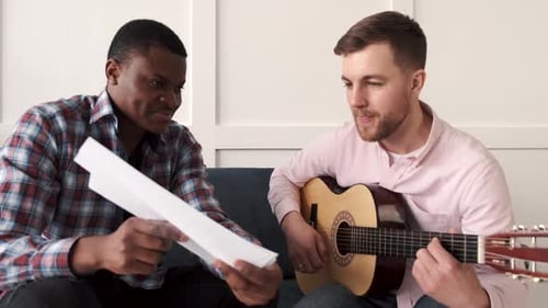 Man Playing Guitar and Singing With Friend Indoors