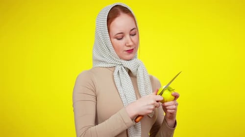 Pretty Young Redhead Woman in Kerchief Cutting Healthful Green Apple and Eating Tasty Fruit at