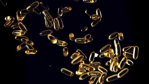 Golden Pills Fall in Slow Motion on Black