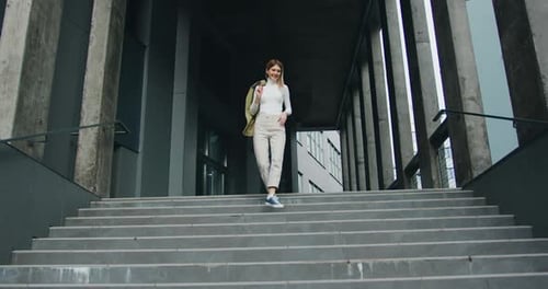 Hermosa joven baja las escaleras sonriendo durante una caminata maravillosa en un día positivo