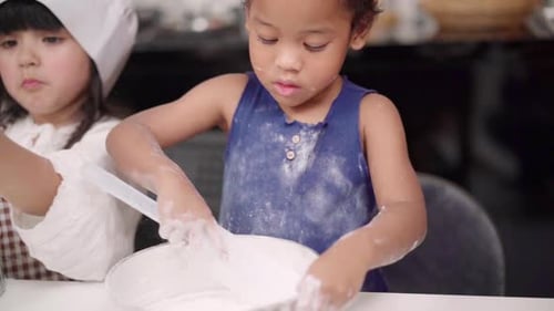 Gruppe von Kindern, die gemeinsam Kuchen im Klassenzimmer backen, multiethnische Jungen und Mädchen machen glücklich beim Backen.