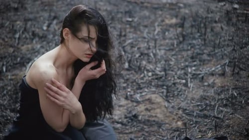 Sad Woman Kneeling in Burnt Field