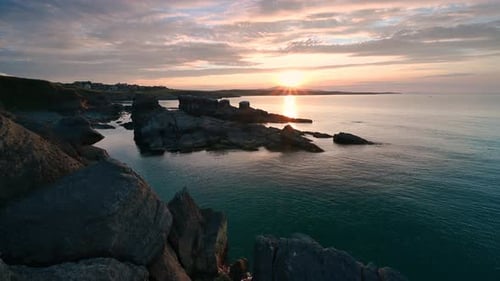 Video with colorful sunset sky at rocky coastline
